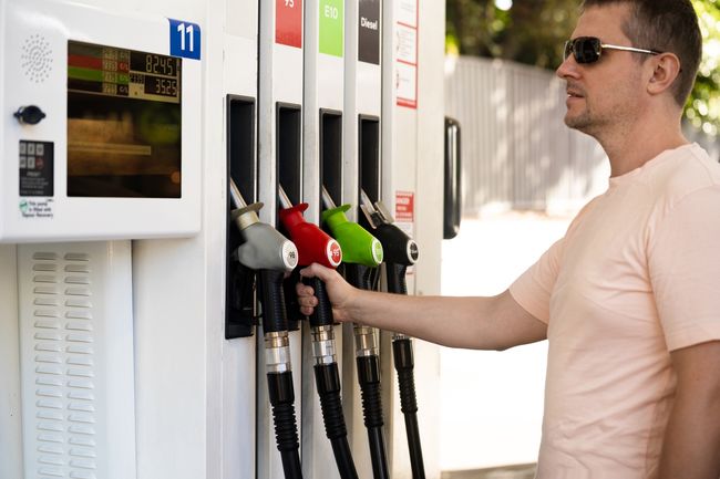 Man at a petrol pump, having just returned the hose to the holster