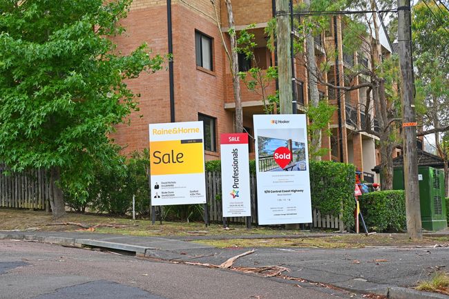 A block of flats with multiple For Sale and Sold signs out the front