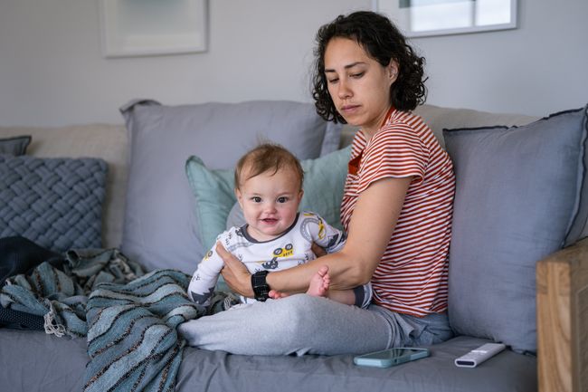Woman sat on a couch holding a young baby