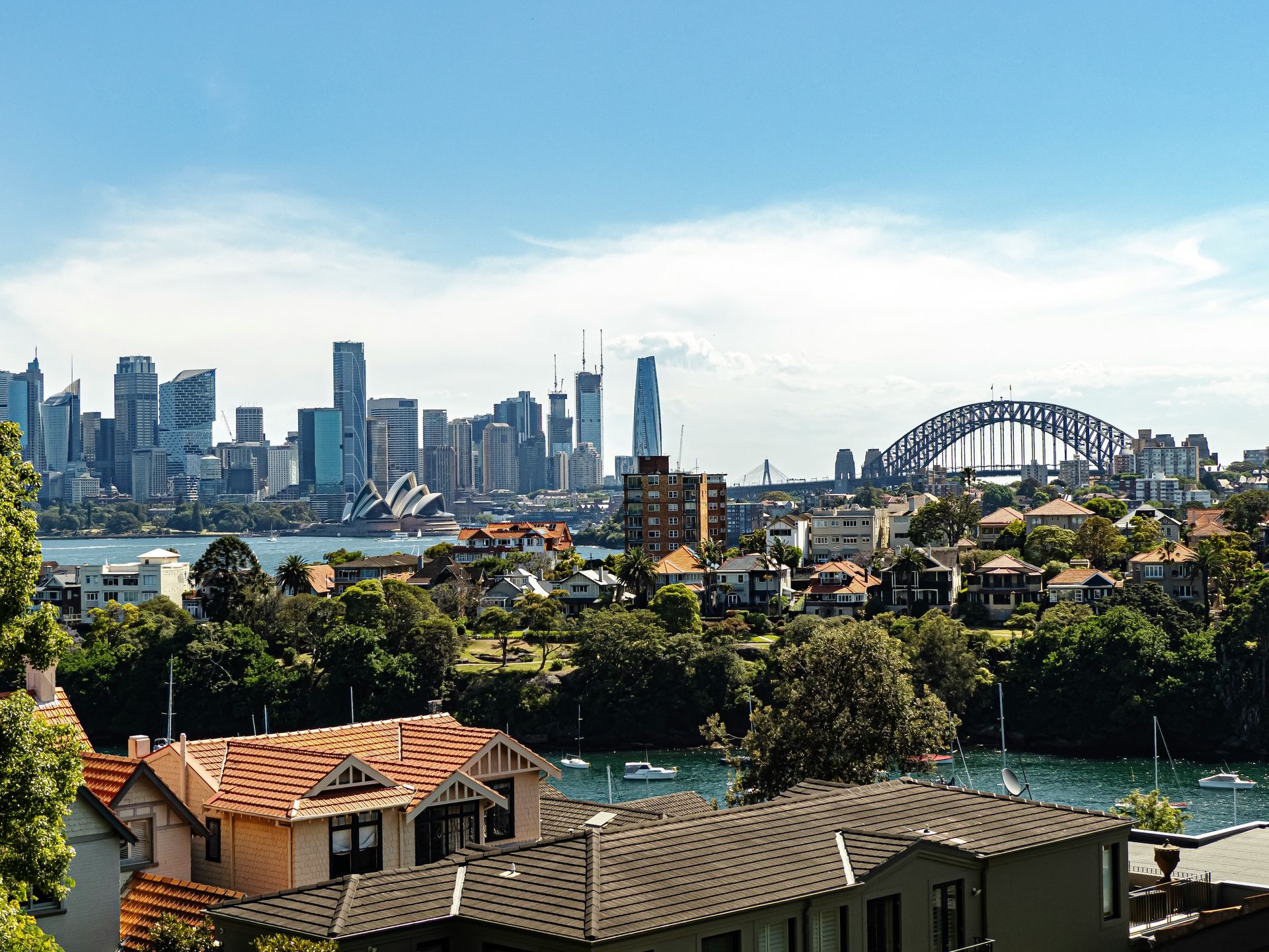 Sydney Harbour from the north under blue skies with a smattering of cloud